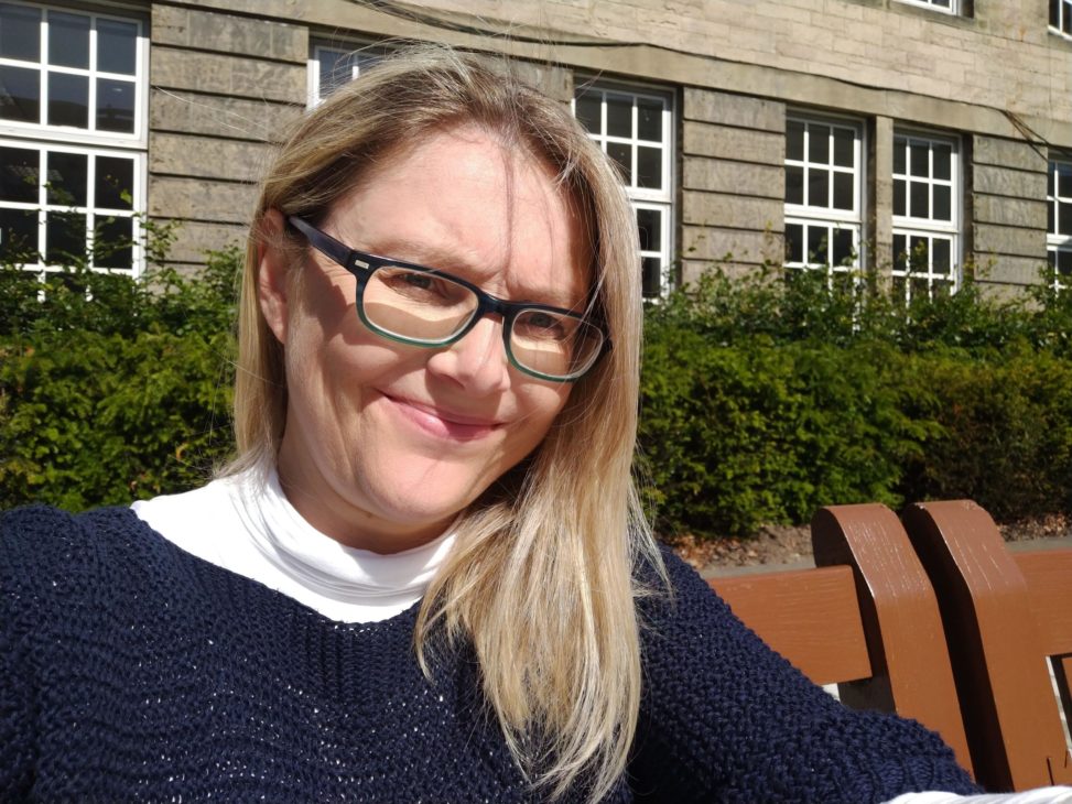 person sitting in a garden with building behind